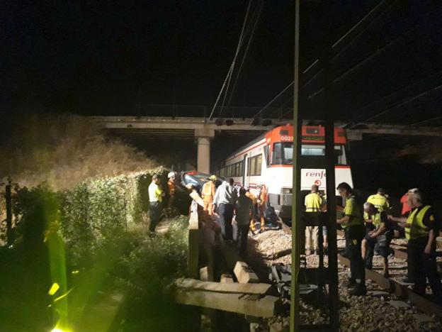 Policías, bomberos y guardias civiles rodean el vehículo en el que viajaba Javier, ayer, estrellado junto a las vías del tren. 