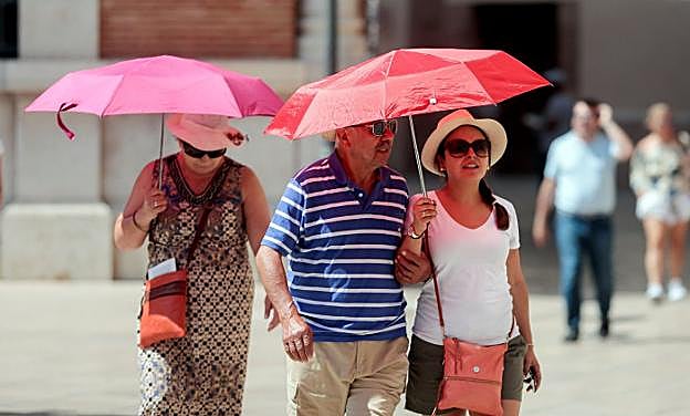 Varias personas se protegen del sol en Valencia. 