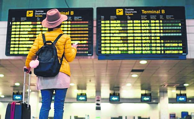 Una turista consulta el panel de destinos en un aeropuerto