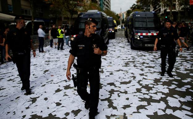 Mossos d'Esquadra andado por una calle cubierta de papeletas del referendum del 1-O. 