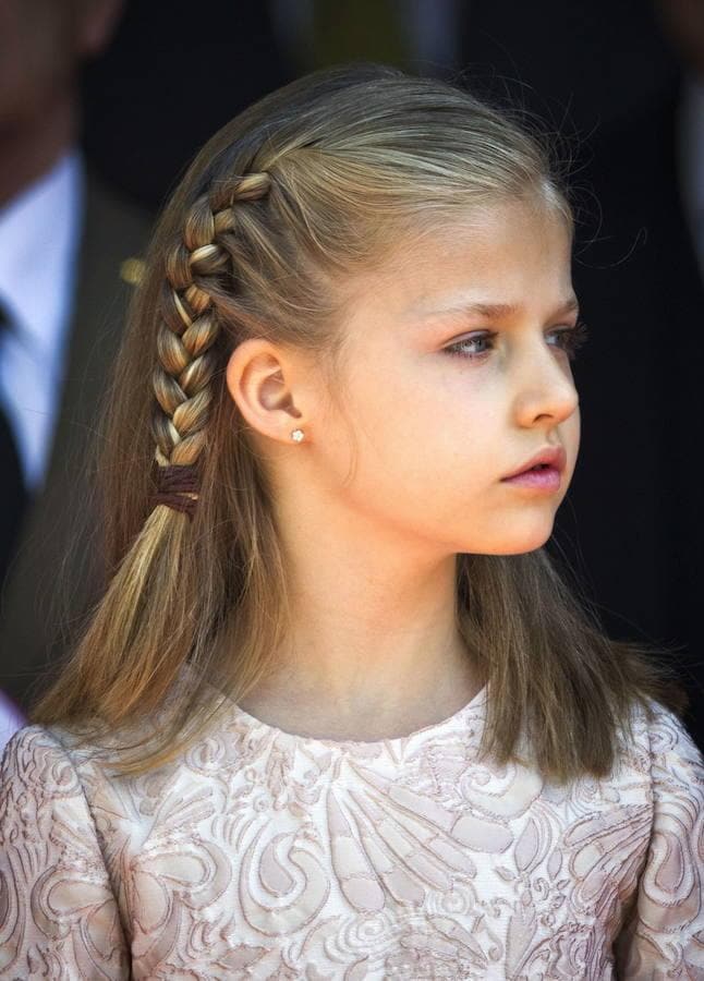 A pesar de utilizar diferentes vestidos, la princesa Leonor lleva siempre el mismo estilo de peinado. Trenzas de espiga y de raíz combinadas con trozos de pelo suelto, que le recogen el cabello. La princesa de doce años, al igual que su hermana la infanta Sofía, tiene el pelo muy fino, por lo que las trenzas son una buena opción para tener siempre una imagen perfecta.