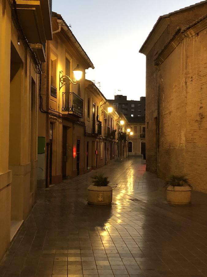 Es una de esas zonas poco conocidas de Valencia. El barrio de Campanar reúne todas esas características que se espera encontrar en un remoto y solitario pueblo, y no en plena urbe. Calles tranquilas, casas antiguas, fachadas con un encanto diseñado por el paso del tiempo. Recorrer sus aceras es pasear por un rincón de paz, ajeno al constante ajetreo de la ciudad. Una especie de paréntesis entre el tráfico, ruido y bullicio, en un lugar donde el reloj parece detenerse, mientras las sombras del atardecer se van colando por cada resquicio. Entre paredes blancas, tonalidades ocre, fuentes y ventanas que se asoman a décadas de historia, permanecen mosaicos en honor a lo que el pueblo fue. Azulejos que recuerdan al oficio hornero y la patrona, la Virgen de Campanar, cuelgan de paredes en las que los ladrillos soportan más años que peso. Casas, unas bajas y otras ilustres, que recuerdan un tiempo no tan lejano, muestras de la Valencia pasada rodeadas de la ciudad actual. 