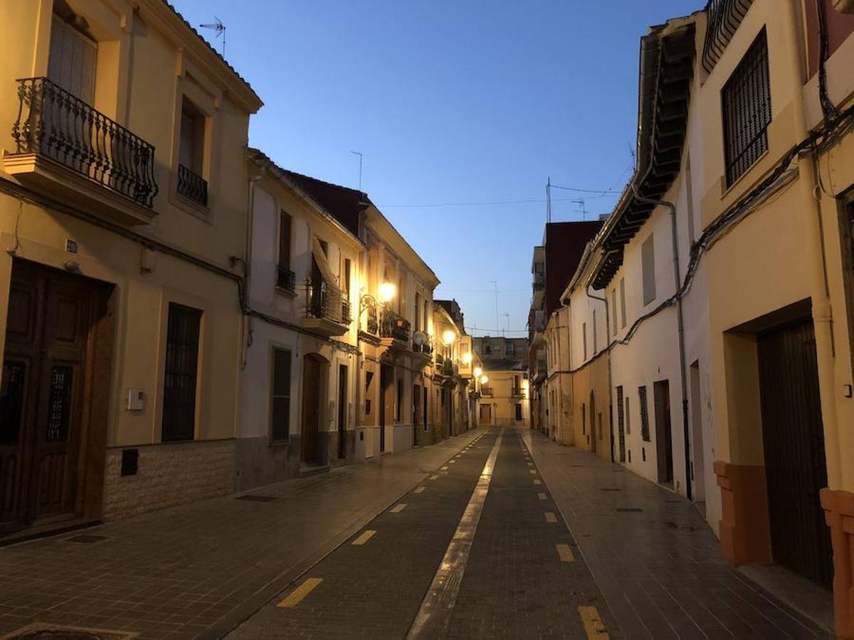 Es una de esas zonas poco conocidas de Valencia. El barrio de Campanar reúne todas esas características que se espera encontrar en un remoto y solitario pueblo, y no en plena urbe. Calles tranquilas, casas antiguas, fachadas con un encanto diseñado por el paso del tiempo. Recorrer sus aceras es pasear por un rincón de paz, ajeno al constante ajetreo de la ciudad. Una especie de paréntesis entre el tráfico, ruido y bullicio, en un lugar donde el reloj parece detenerse, mientras las sombras del atardecer se van colando por cada resquicio. Entre paredes blancas, tonalidades ocre, fuentes y ventanas que se asoman a décadas de historia, permanecen mosaicos en honor a lo que el pueblo fue. Azulejos que recuerdan al oficio hornero y la patrona, la Virgen de Campanar, cuelgan de paredes en las que los ladrillos soportan más años que peso. Casas, unas bajas y otras ilustres, que recuerdan un tiempo no tan lejano, muestras de la Valencia pasada rodeadas de la ciudad actual. 