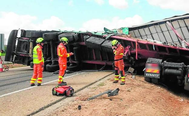 Tres bomberos del Consorcio Provincial de Valencia, ayer, junto a uno de los vehículos obstaculizando la A-3 en Caudete de las Fuentes.