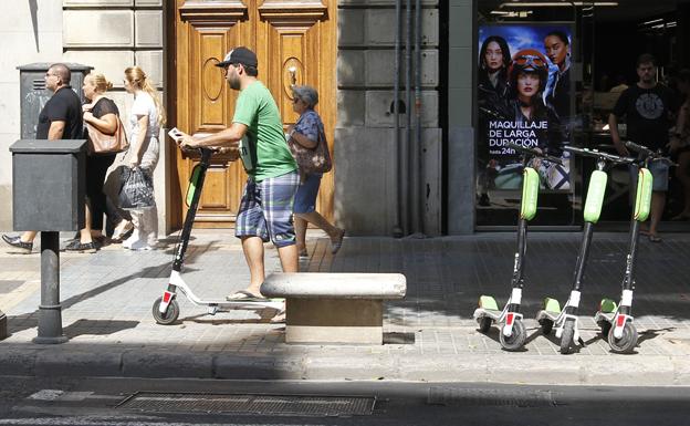 Un hombre, justo tras coger uno de los patinetes de alquiler que hay por el centro de Valencia.