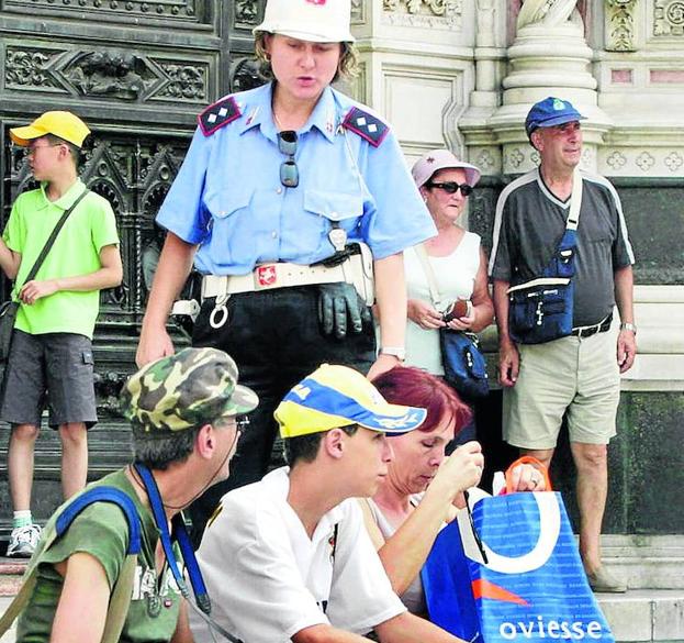 Una policía hace levantarse a unos turistas de unas escalinatas. 