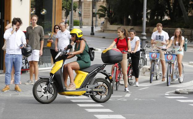 Una moto de alquiler pasa por delante de un grupo de ciclistas en bicis también alquiladas 