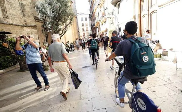Un ciclista circula por la acera en el centro histórico de Valencia.