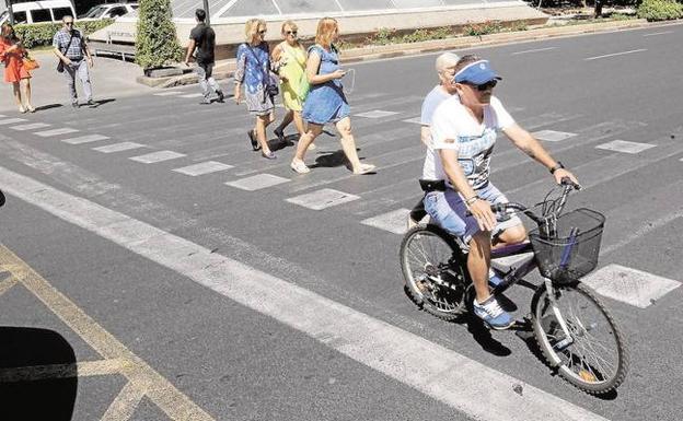 Un ciclista cruza un paso de peatones sin bajar de la bicicleta.