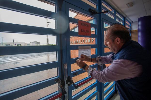 El conserje de un instituto de Vila-real coloca el aviso de la suspensión de las clases. 