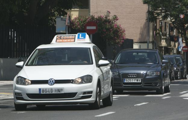 Un coche de autoescuela avanza por una calle de Valencia. 