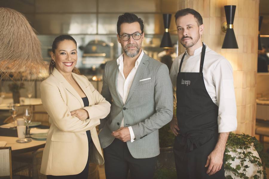 La cocina de producto de Quique Dacosta se instala en pleno centro histórico de Valencia. El cocinero de tres estrellas Michelin amplía su oferta gastronómica en la ciudad con Llisa negra, un restaurante situado en el número 10 de la Calle Pascual y Genís que abre sus puertas a partir de este jueves 15 de noviembre. La cocina de Llisa negra es simple y directa. La parrilla, las brasas y el fuego adquieren el protagonismo a la hora de mimar el producto, generando una cocina en vivo que el cliente podrá observar desde su mesa. La carta ofrece una selección procedente de las lonjas de proximidad y otras de excelente producto. Allí se podrá disfrutar de las gambas hervidas en agua de mar o al Josper, las quisquillas a la brasa, la pata de pulpo de roca de Dénia a la parrilla o la raya adobada al grill, entre otros productos de gran calidad.