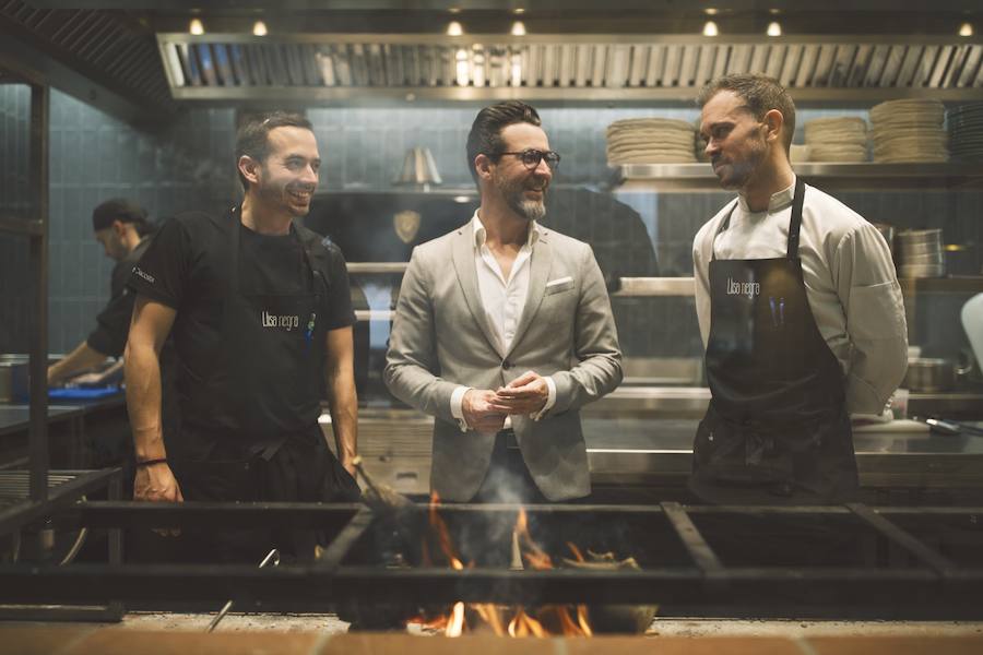 La cocina de producto de Quique Dacosta se instala en pleno centro histórico de Valencia. El cocinero de tres estrellas Michelin amplía su oferta gastronómica en la ciudad con Llisa negra, un restaurante situado en el número 10 de la Calle Pascual y Genís que abre sus puertas a partir de este jueves 15 de noviembre. La cocina de Llisa negra es simple y directa. La parrilla, las brasas y el fuego adquieren el protagonismo a la hora de mimar el producto, generando una cocina en vivo que el cliente podrá observar desde su mesa. La carta ofrece una selección procedente de las lonjas de proximidad y otras de excelente producto. Allí se podrá disfrutar de las gambas hervidas en agua de mar o al Josper, las quisquillas a la brasa, la pata de pulpo de roca de Dénia a la parrilla o la raya adobada al grill, entre otros productos de gran calidad.