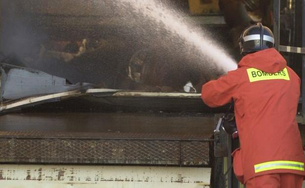 Imagen de archivo de un bomberos sofocando un incendio industrial.