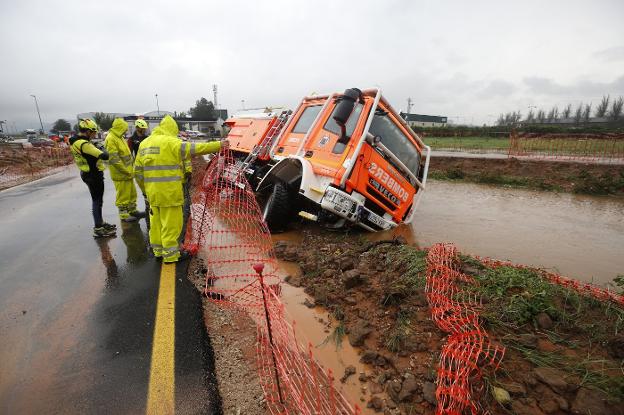 Uno de los camiones de los bomberos que quedó atrapado en el canal que discurre junto a la carretera CV-50, ayer, en Alzira. 