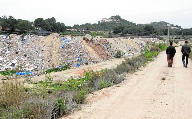 Dos vecinos pasean y observan en 2010 el estado del macrovertedero que llevaba seis años en una zona de la población alicantina de San Miguel de Salinas ante la permisividad institucional. 