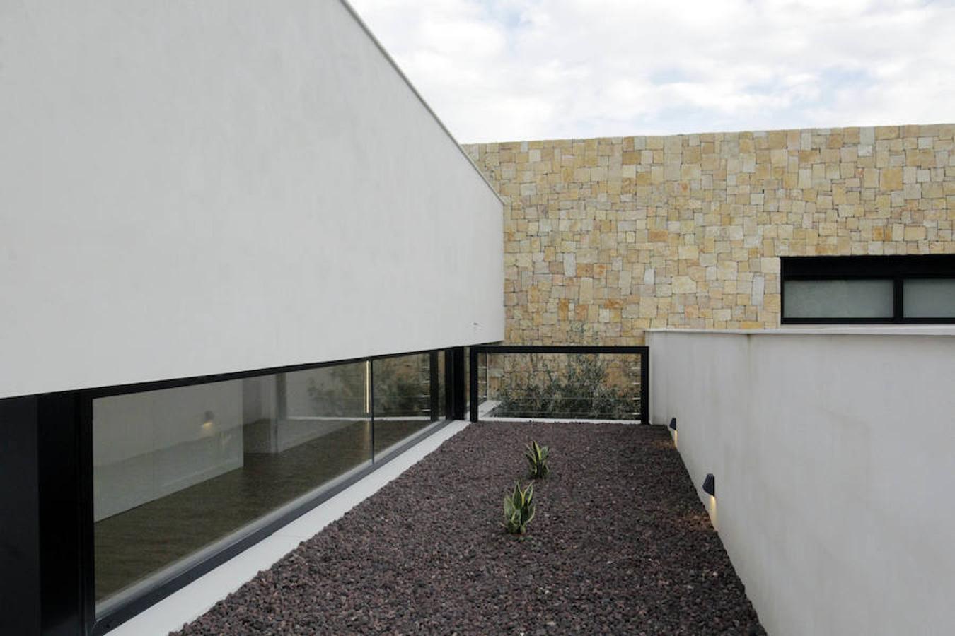 Cuando Antonio y Carolina se plantearon construir un nuevo hogar vieron una casa obra del arquitecto Jaime Chiralt que combinaba la piedra con el blanco. En ese momento le llamaron para encargarle el proyecto y juntos dieron con la parcela rectangular que hoy acoge su vivienda en una urbanización a las afueras de Valencia. Les conquistó la ubicación y decidieron derruir la casa que había para empezar de cero. La piedra es el verdadero elemento vertebrador que regula el espacio. El blanco, el negro y la madera predominan en toda la casa creando una sincronía cromática muy estética y equilibrada. 