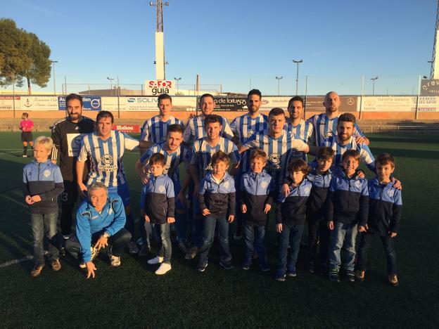 La plantilla del CF Gandia junto a los niños de un equipo de la cantera del club. 
