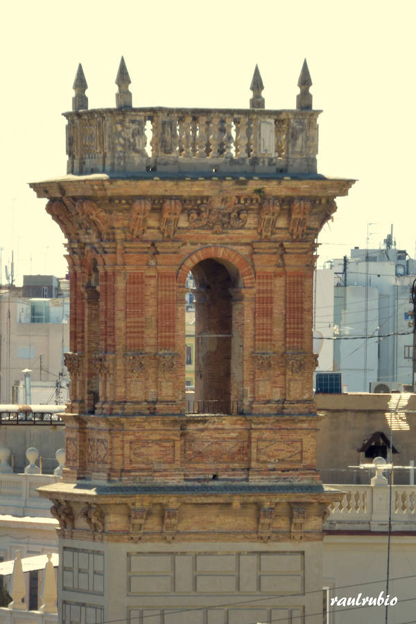 Valencia nunca deja de sorprender. Es habitual la imagen desde la calle de los múltiples campanarios que se encuentran en la ciudad. En el centro histórico aún encontramos más torreones eclesiásticos. Pero, ¿cómo se ve la ciudad desde el cobijo de las campanas?. Raúl Rubio, de la Associació de Mestres Campaners, ha inmortalizado esa visión de la que poca gente puede disfrutar: Valencia desde sus campanarios. Ver la plaza de San Agustín con una perspectiva diferente, contemplar el centro de la ciudad desde Santa Catalina, admirar Valencia desde las campanas del Real Monasterio de la Santísima Trinidad son algunos de las panorámicas exquisitas casi exclusivas para campaneros. La ciudad se redescubre desde las alturas, desde la perspectiva de gárgolas, campanas y tejados. Así es Valencia desde sus campanarios.