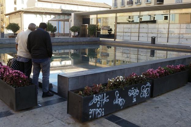 Lámina de agua de la plaza de la Almoina, con pintadas en una jardinera. 