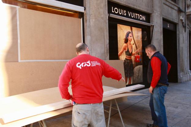 Dos trabajadores reparan el escaparate que rompieron los ladrones a mazazos en la calle Poeta Querol de Valencia. 