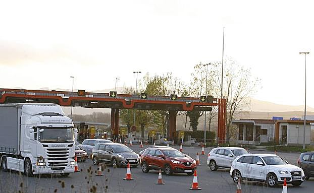 Vehículos pasando un peaje en una autopista.