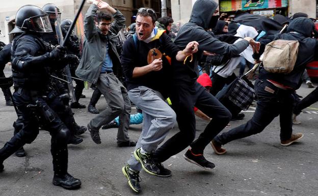 Policías persiguen a varios jóvenes durante las protestas. 