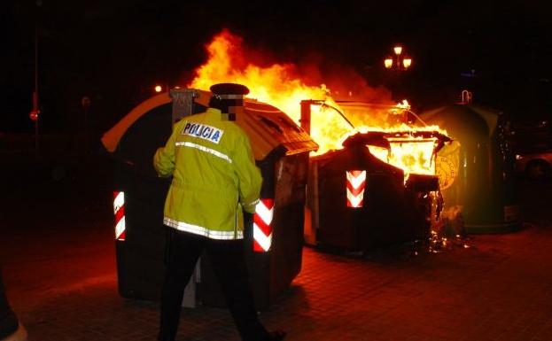 Imagen de archivo de un policía local ante el incendio de un contenedor en Valencia.