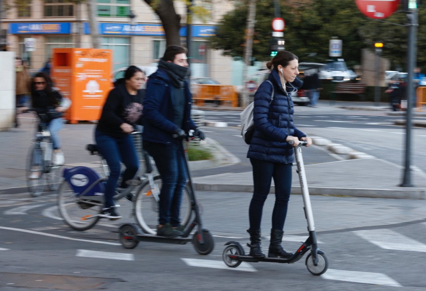 Dos personas circulan por una calle de Valencia con sus patinetes, ayer. 