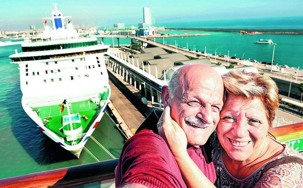 Una pareja madura inmortaliza con un selfi su entusiasmo minutos antes de que su crucero leve anclas en el puerto de Barcelona.