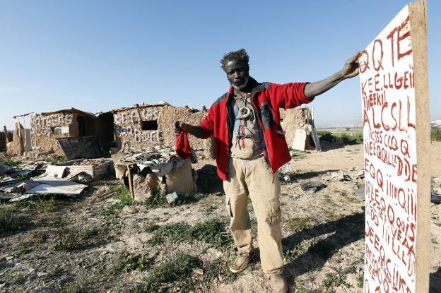 El africano posa al lado de sus arcanas inscripciones, junto a la ampliación de su asentamiento en suelo de propiedad municipal. 