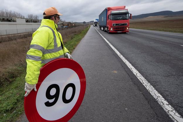 Un operario prepara una de las nuevas señales con el límite de 90 km/h en una carretera secundaria de Álava. 