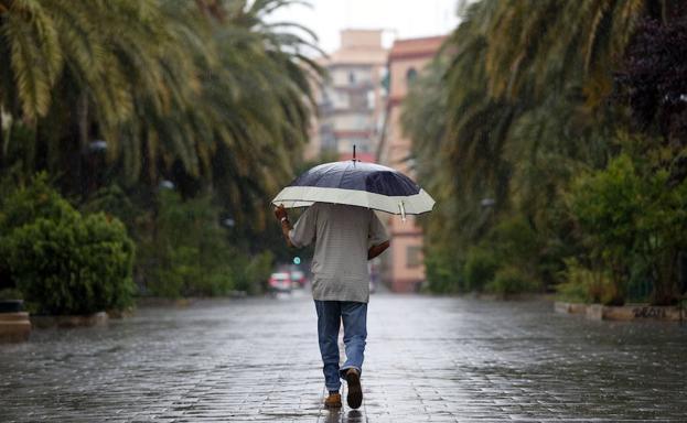 Un hombre se protege de la lluvia en Valencia.