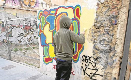Limpieza. Un vecino repinta un muro para borrar unas pintadas, este viernes en una calle del Carmen. 