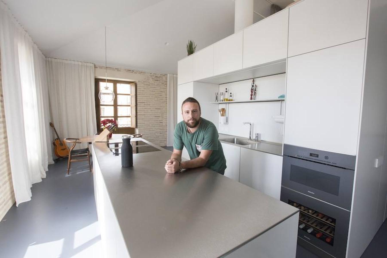 Raúl Cerdán quería vivir en una casa despejada con tantas vistas que se fundiera con el exterior. El resultado es una propiedad modular y adaptable que cambia según las necesidades. El piso, ubicado cerca del mercado de Mossen Sorell, estaba vacío con acabados de obra. Tenía el forjado y las paredes de ladrillo que hubo que limpiar y pulir. Las contraventanas que instalaron son una réplica exacta de las que había para así guardar una continuidad con la esencia de la casa original y del barrio. «Era una vivienda pequeña y la manera en la que estaban comunicados los espacios tenía magia, la idea era no perder esa conexión. Mi propuesta fue ubicar un cubo de madera en la parte central que vehiculase el espacio de la vivienda», explica Borja Hernández, co fundador del estudio de diseño Nada Design. La decisión fue crear un loft con un baño en la parte interior y una habitación supletoria que ejerce a su vez de espacio multifuncional en la planta principal. En la altura superior se instaló otro baño y la habitación principal con un sistema de oscurecimiento que la independiza del resto cuando se desea. Para Raúl era fundamental la cocina, pues además de gustarle cocinar, en su opinión es el corazón de la casa.«El bloque de la cocina condicionó el resto de la casa. Los acabados lineales en blanco marcan la pauta de la armariada que ocupa la pared principal. La ubicación, además, se ideó para que mientras cocinas tengas unas vistas espectaculares de barrio de Carmen», detalla Raúl Cerdán, experto en transporte y logística. La escalera está pensada para que no quite protagonismo al conjunto de la vivienda en sí. 