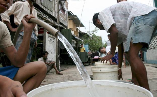 Varios residentes de Yangon (Birmania) llena cubos con agua potable de un pozo. 