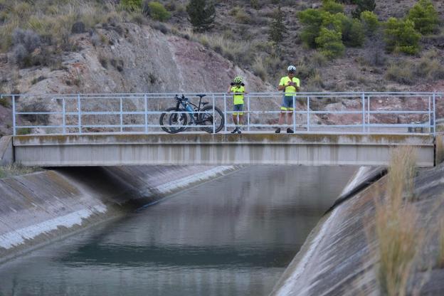 Dos ciclistas descansan en un puente sobre los conductos de agua del trasvase Tajo-Segura. 