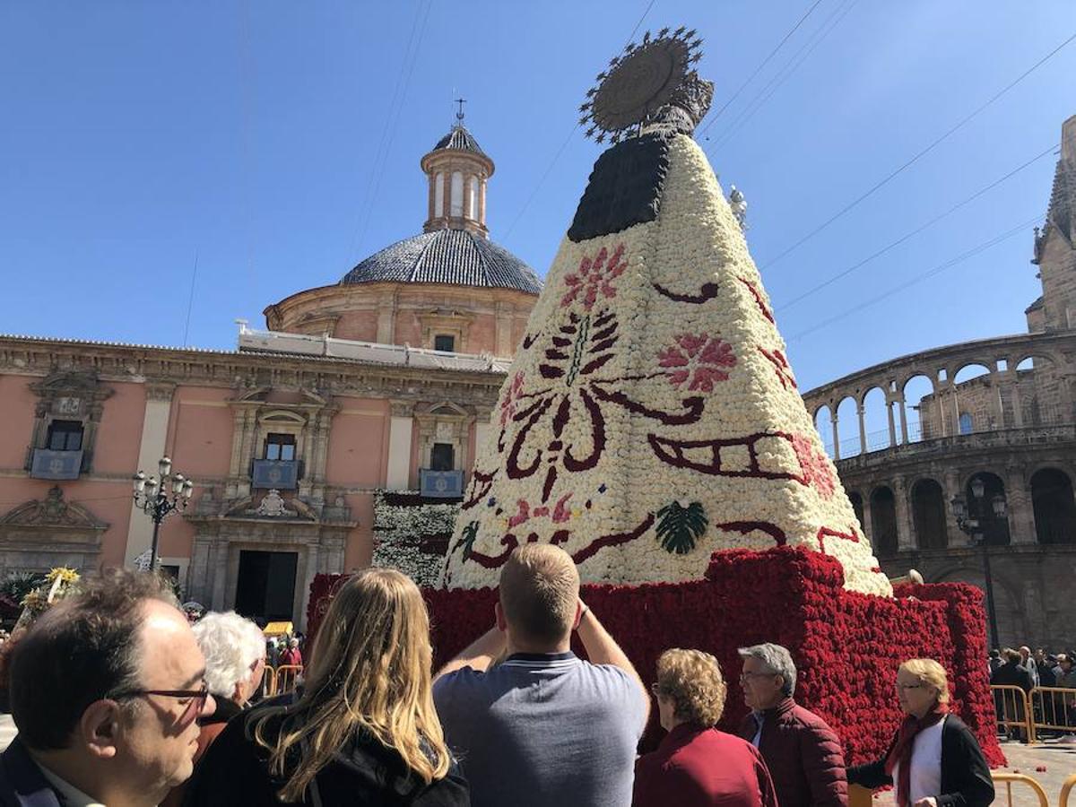 La Ofrenda concluyó este lunes después de que miles de falleros desfilaran para llevar las flores a la Virgen de los Desamparados. Este martes, a la luz del día se ha desvelado ante los ojos de los valencianos el aspecto definitivo del manto de la 'Geperudeta'. Claveles blancos, rojos y rosas componen componen el diseño del vestidor Rafael Chordá. Un floreado manto con el blanco como color predominante y que preside estos días la plaza de la Virgen, ante su basílica.