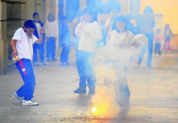 Un grupo de niños se divierten haciendo estallar petardos contra el suelo en una calle de Valencia. 