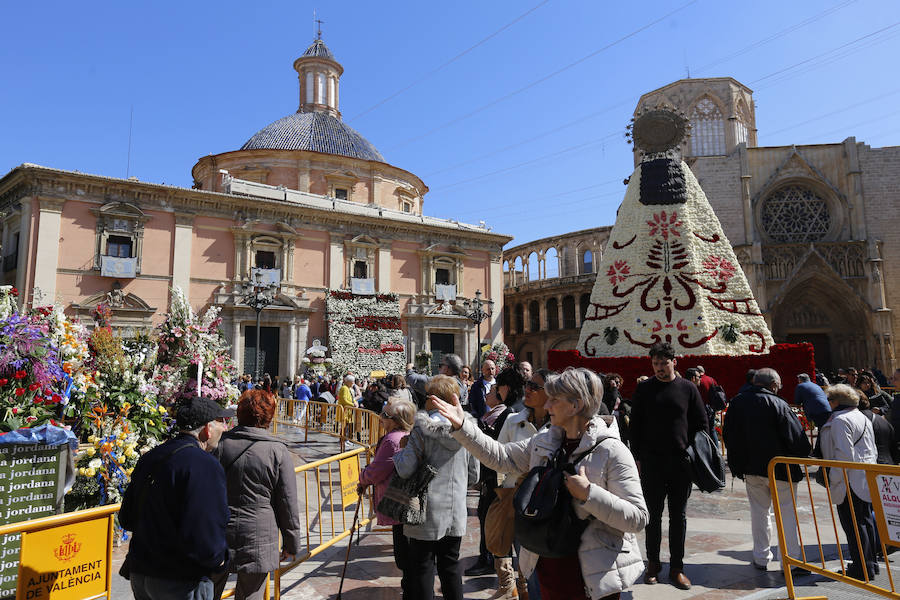 La Ofrenda concluyó este lunes después de que miles de falleros desfilaran para llevar las flores a la Virgen de los Desamparados. Este martes, a la luz del día se ha desvelado ante los ojos de los valencianos el aspecto definitivo del manto de la 'Geperudeta'. Claveles blancos, rojos y rosas componen componen el diseño del vestidor Rafael Chordá. Un floreado manto con el blanco como color predominante y que preside estos días la plaza de la Virgen, ante su basílica.