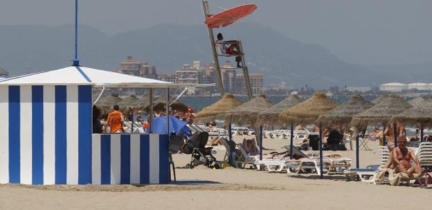 Posta de la Cruz Roja en la playa de la Malvarrosa, rodeada de hamacas y un quiosco. 