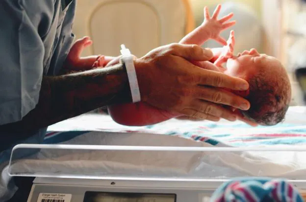 Un ginecólogo sostiene a un niño recién nacido en un quirófano. 