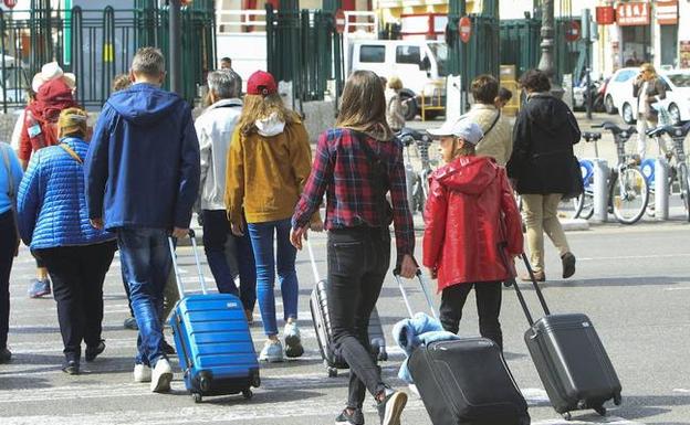 Visitantes y vecinos de Valencia cargados con maletas. 