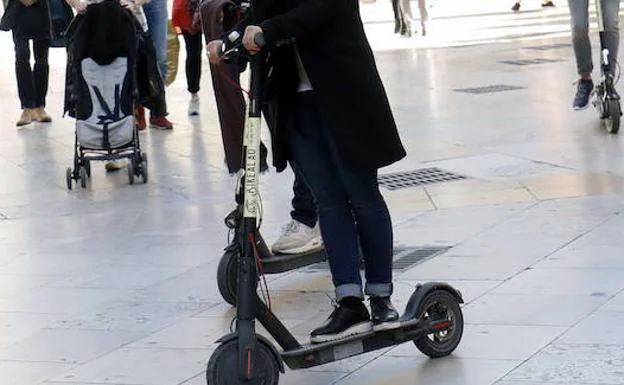 Una mujer circula en patinente eléctrico por la acera en Valencia. 