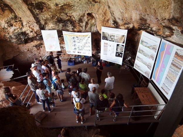 Un grupo de visitantes atendiendo a las explicaciones de una experta en la Cova del Bolomor. 