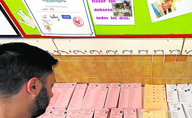 Un ciudadano elige papeleta para votar. 