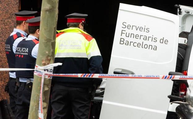 Los Mossos esperan en el portal del inmueble donde murió el hombre tiroteado, en Barcelona.