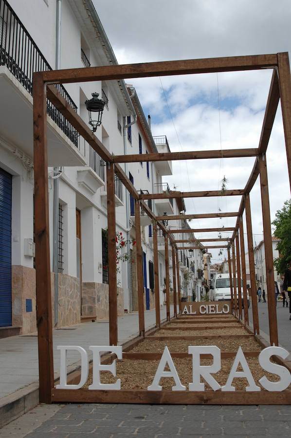 Los aromas y colores de las flores se han adueñado de Aras de los Olmos (Valencia). Durante la primavera, esta localidad situada Los Serranos cubre sus calles, fachadas con cientos de plantas y arte efímero. La exposición de las propuestas presentadas en «Aras en flor» se podrá visitar hasta el 30 de junio Los diseñadores de paisajes han tenido que defender la sostenibilidad, belleza y creatividad de la propuesta. Además de combinar flores y plantas con materiales del entorno utilizados históricamente por los vecinos y vecinas. Esta pequeña localidad del interior de la Comunitat Valenciana aguarda entre montes como un remanso de paz que fue poblado por íberos, romanos y árabes, Incluso, formó parte de la Orden de Montesa en 1318. Y todas estas culturas se han quedado guardadas entre sus callejuelas. 