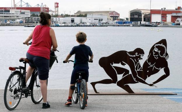 Una mujer y un menor observan una escultura. 