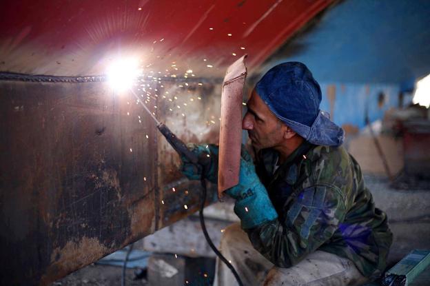 Un trabajador soldando dos piezas de metal. 